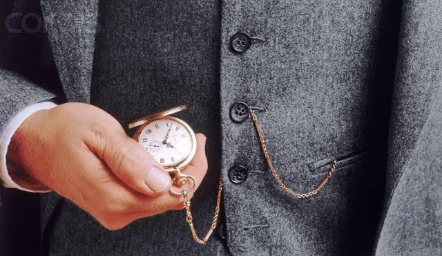 Man in a gray suit holding a pocket watch.
